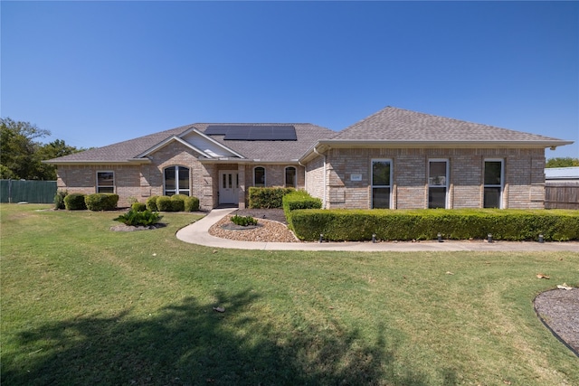 ranch-style house with a front yard and solar panels