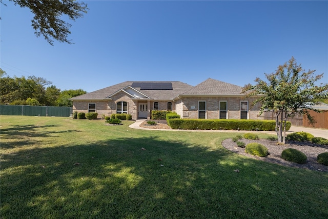 view of front of property with a front yard and solar panels