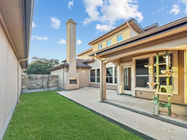 back of property with a lawn, a fireplace, and a patio area