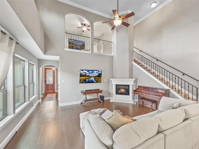 living room featuring crown molding, ceiling fan, hardwood / wood-style floors, and a high ceiling