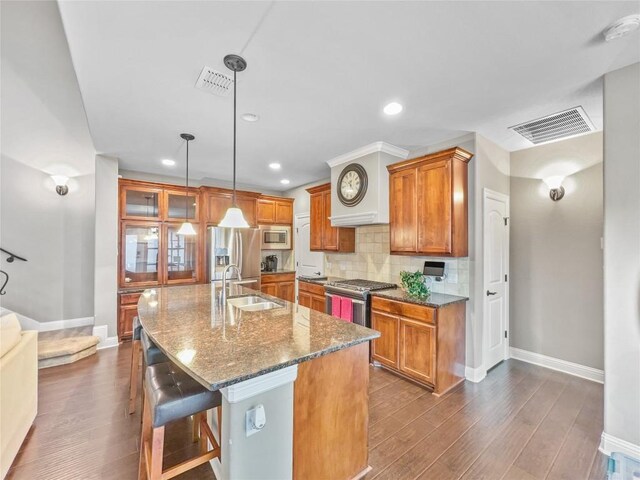 kitchen with sink, a breakfast bar area, hanging light fixtures, appliances with stainless steel finishes, and an island with sink