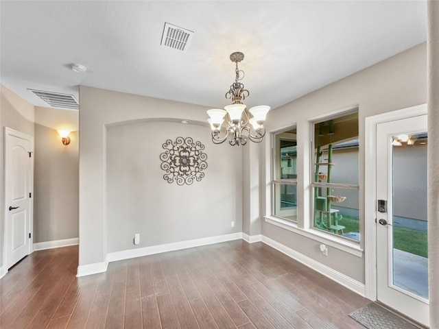 unfurnished dining area with dark wood-type flooring and an inviting chandelier