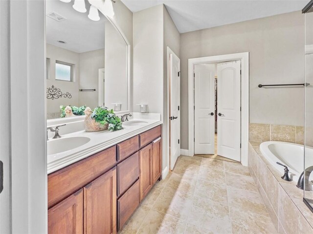 bathroom featuring a relaxing tiled tub and vanity