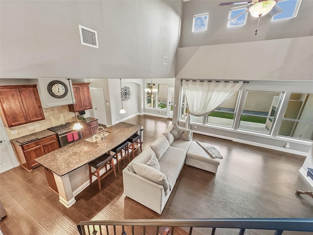 living room featuring a high ceiling, sink, ceiling fan with notable chandelier, and dark hardwood / wood-style flooring