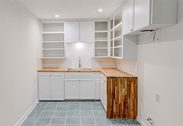 kitchen featuring butcher block counters, decorative backsplash, white cabinetry, and sink