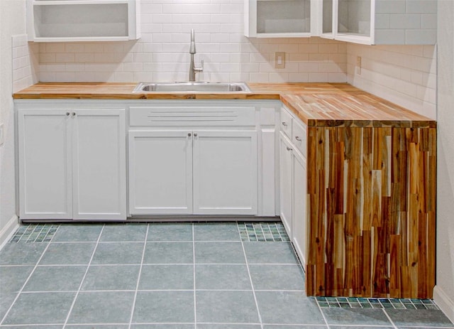 kitchen with tasteful backsplash, butcher block countertops, sink, and white cabinetry