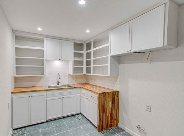 kitchen with tasteful backsplash, sink, white cabinetry, and butcher block counters