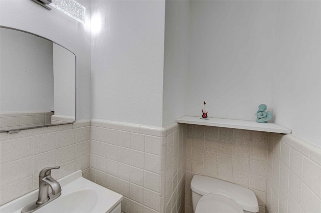 bathroom with vanity, tile walls, and toilet