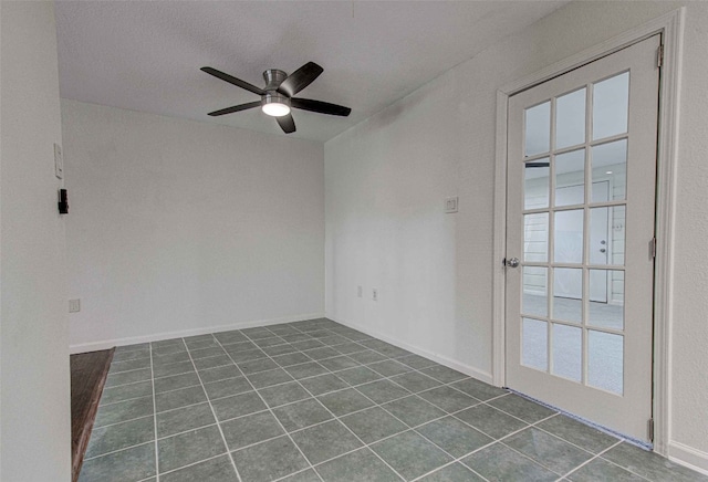 unfurnished room with a textured ceiling, dark tile patterned flooring, and ceiling fan