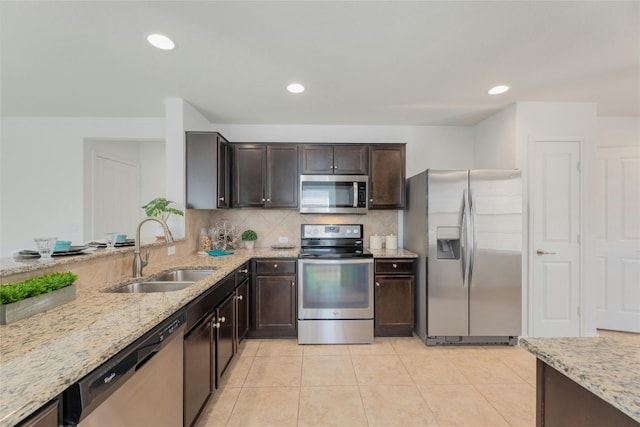 kitchen featuring decorative backsplash, appliances with stainless steel finishes, light stone countertops, sink, and light tile patterned flooring