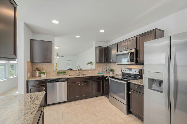 kitchen featuring sink, ceiling fan, decorative backsplash, light stone counters, and stainless steel appliances