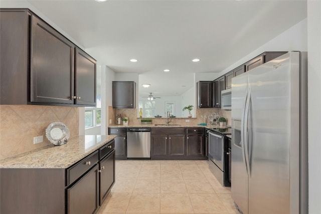 kitchen featuring sink, ceiling fan, light stone countertops, light tile patterned floors, and stainless steel appliances