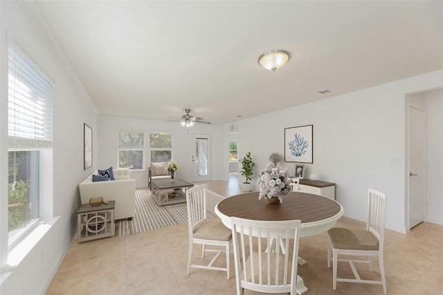 dining space with crown molding, ceiling fan, and light tile patterned flooring