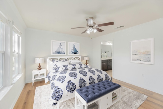 bedroom featuring ensuite bathroom, light hardwood / wood-style flooring, multiple windows, and ceiling fan