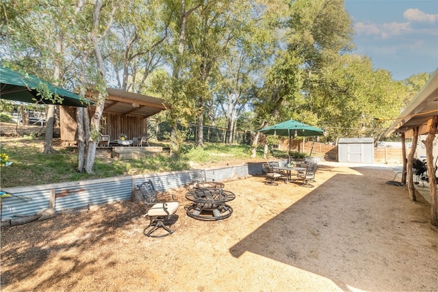 view of patio with an outdoor fire pit and a storage unit