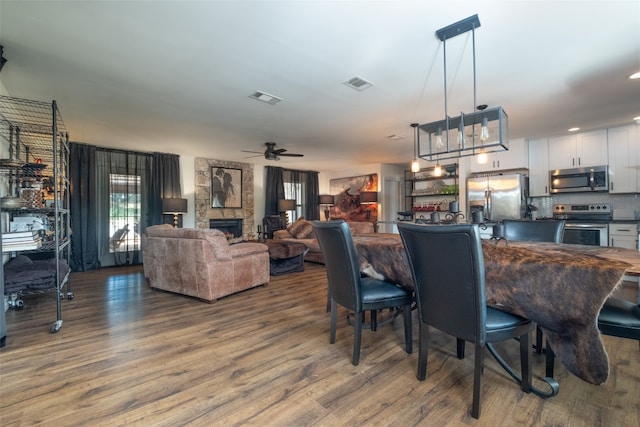 dining area featuring a fireplace, hardwood / wood-style floors, and ceiling fan