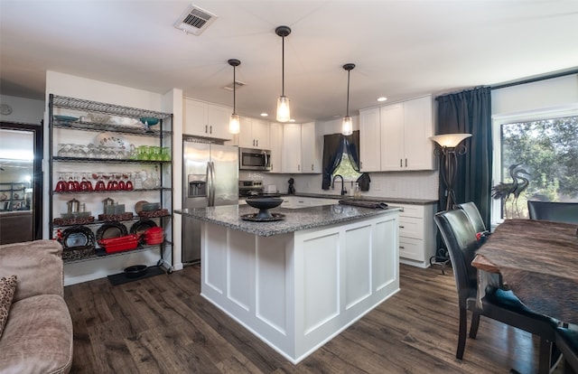 kitchen featuring appliances with stainless steel finishes, white cabinetry, decorative light fixtures, and dark hardwood / wood-style flooring