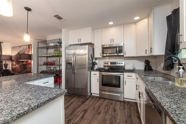 kitchen featuring stainless steel appliances, white cabinets, sink, dark hardwood / wood-style flooring, and hanging light fixtures