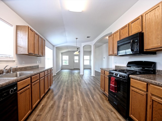 kitchen featuring lofted ceiling, hanging light fixtures, sink, dark wood-type flooring, and black appliances