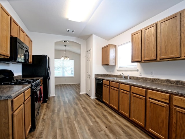 kitchen with dark hardwood / wood-style flooring, decorative light fixtures, sink, vaulted ceiling, and black appliances