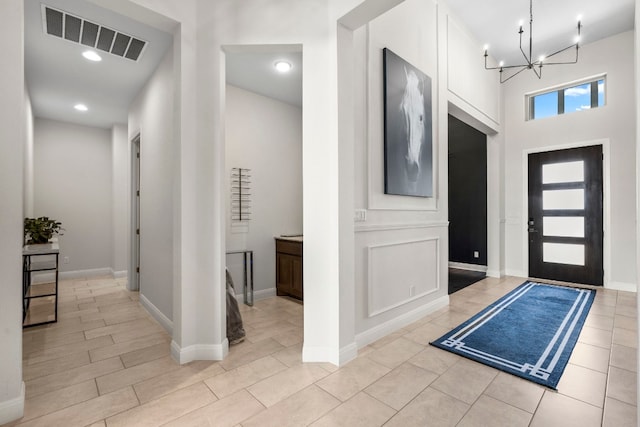 entryway featuring a notable chandelier, light hardwood / wood-style floors, and a towering ceiling