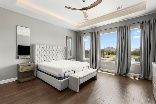 bedroom with dark wood-type flooring, a tray ceiling, and ceiling fan