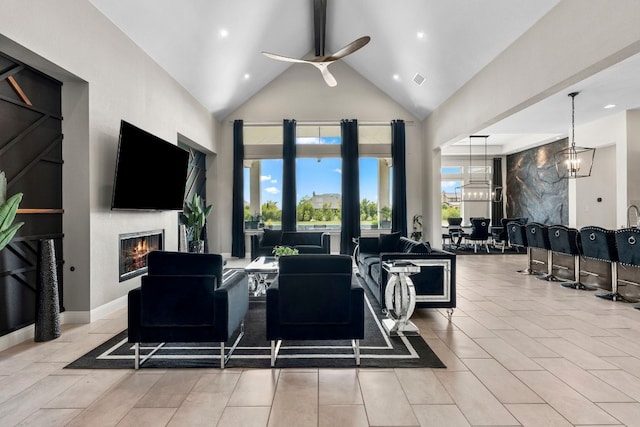 living room featuring ceiling fan with notable chandelier, plenty of natural light, and high vaulted ceiling