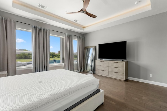 bedroom featuring dark hardwood / wood-style flooring, ceiling fan, and a raised ceiling