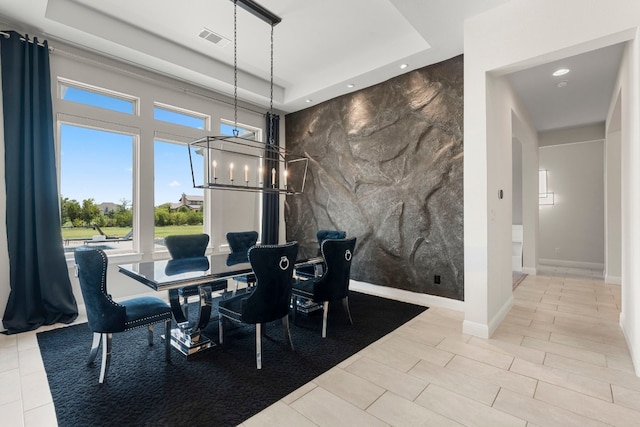 dining area with tile walls, a notable chandelier, and a raised ceiling