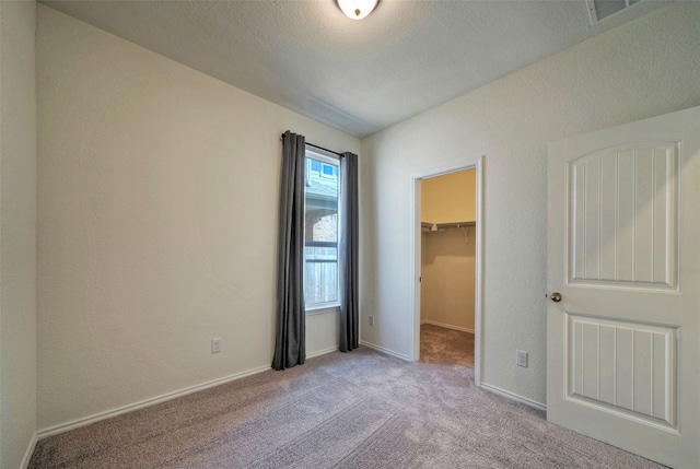 unfurnished bedroom featuring a walk in closet, light carpet, and a closet