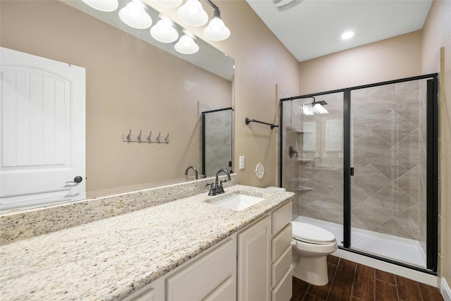 bathroom featuring wood-type flooring, a shower with door, vanity, and toilet