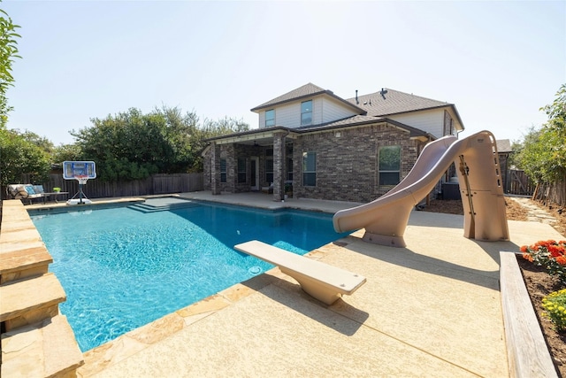 view of pool with a water slide, a diving board, and a patio area