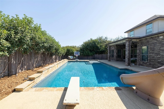 view of swimming pool with a diving board and a patio