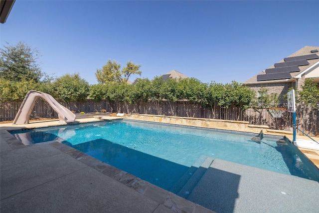 view of swimming pool with a water slide and a patio area