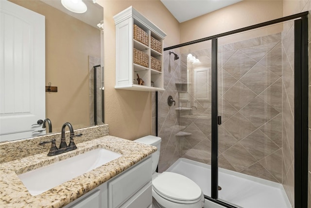 bathroom with vanity, a shower with door, and toilet