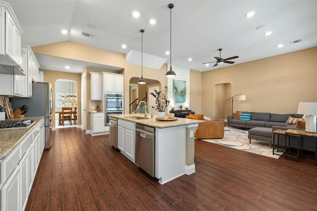 kitchen with white cabinets, an island with sink, hanging light fixtures, dark wood-type flooring, and appliances with stainless steel finishes