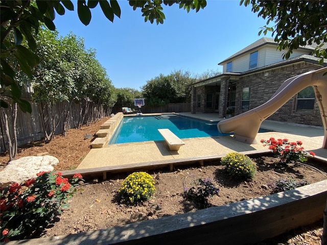 view of pool featuring a water slide, a diving board, and a patio area