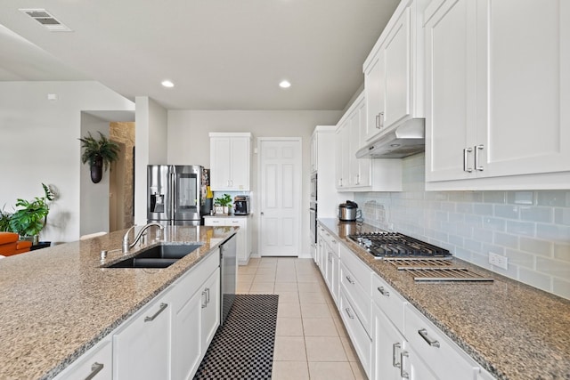 kitchen with white cabinets, appliances with stainless steel finishes, light stone counters, and sink