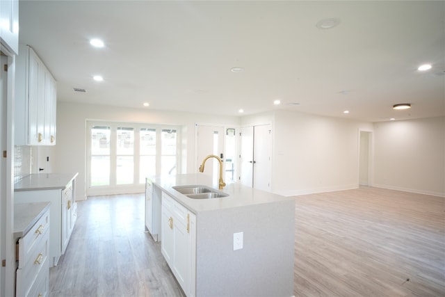 kitchen featuring an island with sink, white cabinetry, and sink