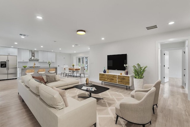 living room with light wood-style floors, visible vents, and recessed lighting