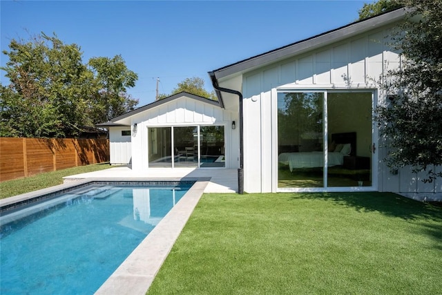 rear view of property featuring a lawn and a fenced in pool