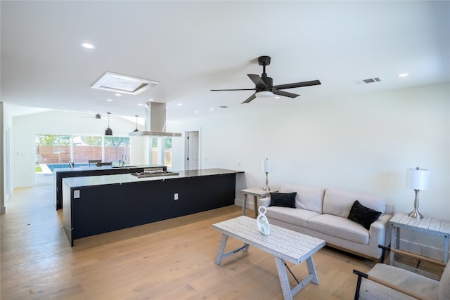 living room with ceiling fan, sink, and light hardwood / wood-style flooring