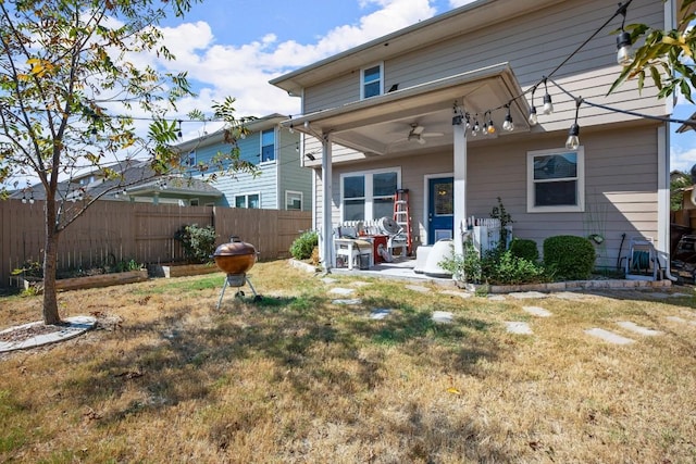 rear view of property featuring ceiling fan, a yard, and a patio