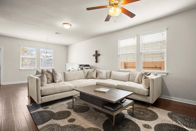 living room with ceiling fan with notable chandelier, a healthy amount of sunlight, and dark hardwood / wood-style flooring