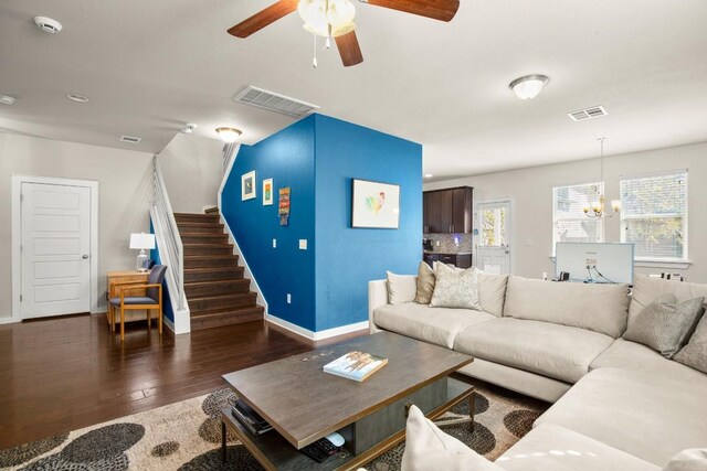 living room featuring ceiling fan with notable chandelier and dark wood-type flooring