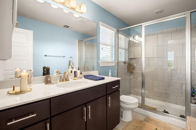 bathroom with toilet, vanity, tile patterned floors, and an enclosed shower