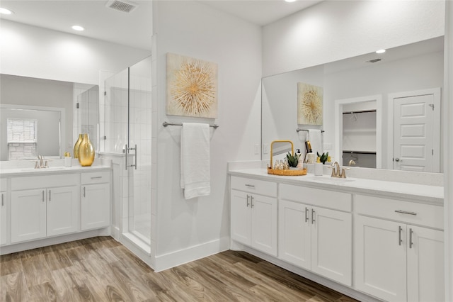 bathroom with hardwood / wood-style floors, a shower with door, and vanity