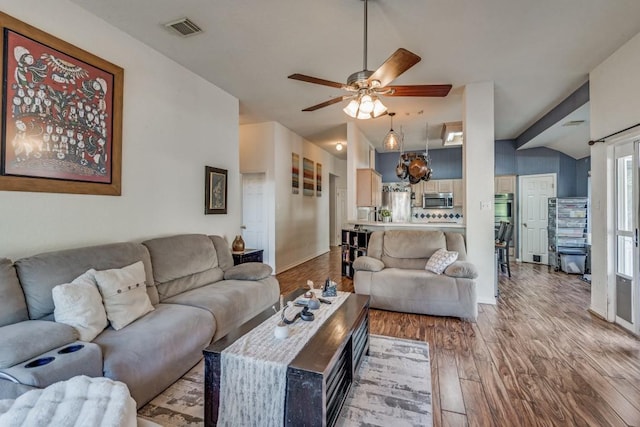 living room featuring wood-type flooring, vaulted ceiling, and ceiling fan