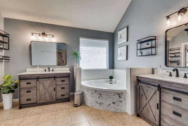 bathroom featuring tile patterned flooring, vanity, tiled bath, and vaulted ceiling