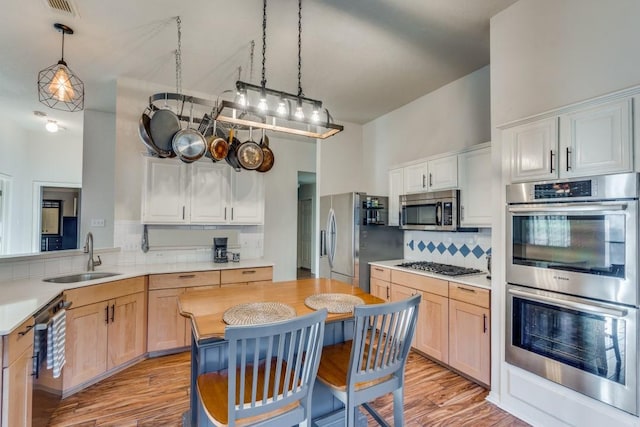 kitchen with sink, pendant lighting, light brown cabinets, and appliances with stainless steel finishes